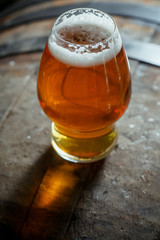 Glass of light beer on a wooden barrel
