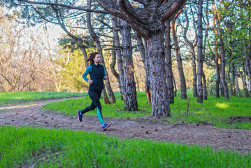 Young woman on a morning run through the spring forest.