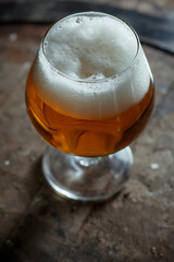 Snifter beer glass on a wooden barrel