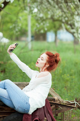 Young attractive woman is busy with her mobile phone doing selfies, writing, reading 