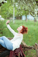 Young attractive woman is busy with her mobile phone doing selfies, writing, reading 