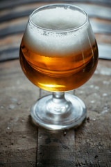 Snifter beer glass on a wooden barrel