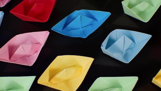 Colorful paper boats. Elevated top view, trucking shot. 4K resolution