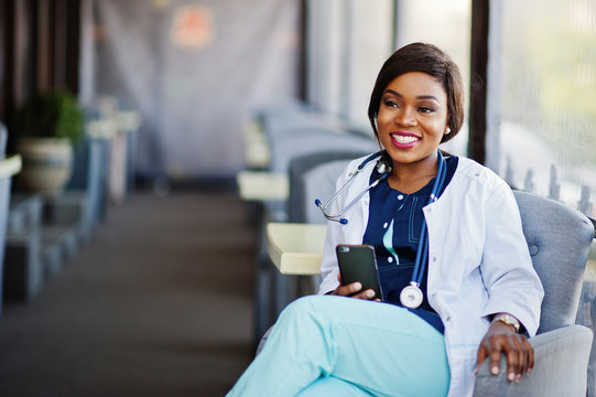 African american doctor female with stethoscope looked at phone and sitting on clinic.