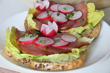 sandwich with smoked ham on a lettuce leaf with slices of radish