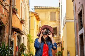 Unrecognizable tourist woman standing and focusing with camera at Trastevere in Rome, Italy.