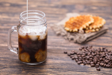 Ice coffee and coffee beans on the background.