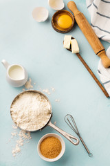 Baking background with ingredients flour, eggs, sugar, butter, cinnamon, anise star and kitchen tools on blue rustic table. Selective focus. Top view.