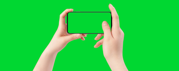 Obraz premium Female hands holding smartphone with empty screen, isolated on green background. The chromakey. Green screen.