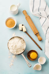 Baking background with ingredients flour, eggs, sugar, butter, cinnamon, anise star and kitchen tools on blue rustic table. Selective focus. Top view.