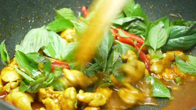 stir fried mix together sweet basil, bell pepper, chicken ,sliced corn , long yard beans,  spices , curry paste and  food palm oil by wooden turner  the black teflon pan