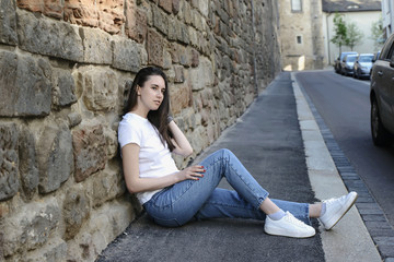 Young beautiful dark-haired girl model appearance in an old town in the spring.