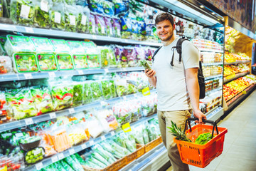 young smiling man choosing products in grocery store. shopping concept. lifestyle