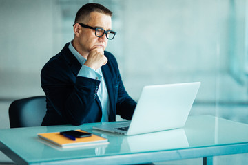 Senior man in modern office working on laptop computer