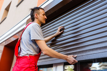 Man installing roller shutter on window
