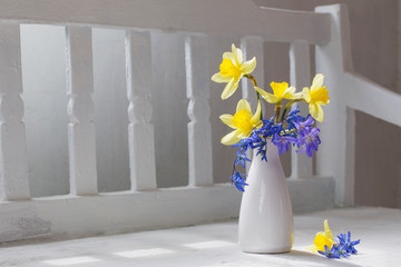 spring flowers in vase on white wooden bench