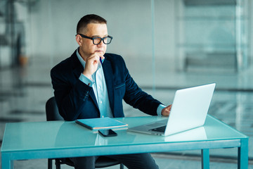 Fototapeta premium Portrait of handsome senior businessman using a laptop while looking at laptop.