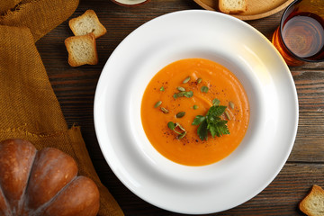 Tasty pumpkin soup in plate on wooden boards