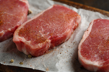 Uncooked meat slice with spice on wood