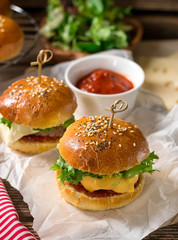 Mini cheeseburgers sliders with ground beef, cheddar, lettuce and tomato sauce