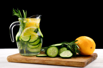 Cold and refreshing detox water with lemon, cucumber, rosemary and ice in glass jar. Copyspace. Banner