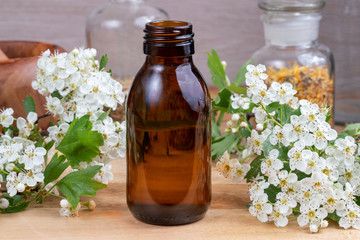 A bottle of tincture with blooming hawthorn branches