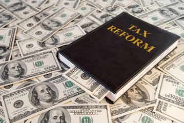 Black book and money with the inscription Tax Reform on dollar banknotes background
