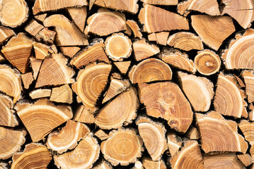 A photo of dry chopped wood, wooden logs for a fire or a fireplace neatly stacked in a pile for the background texture