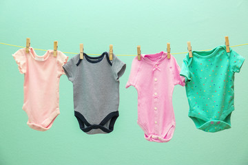 Children's clothes on laundry line against color background