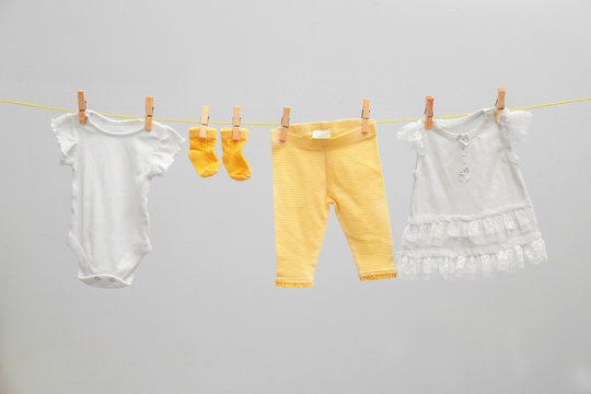Children's clothes on laundry line against light background
