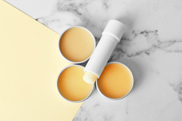Flat lay composition with hygienic lipstick and balms on light background