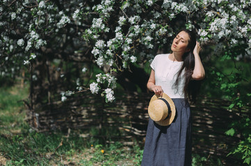 beautiful girl in hat in flowering gardens