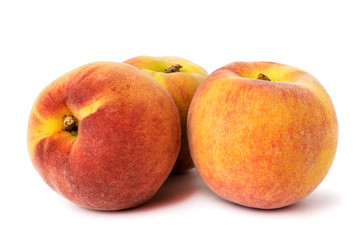 Three ripe peaches with natural shadow on a white, closeup.