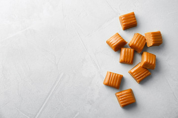 Delicious caramel candies on light background