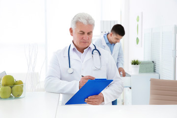 Senior male doctor working at reception desk in hospital