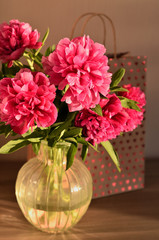 Fresh bouquet of pink peonies peony roses flowers in a vase on table in room. A gift to a mum's day. Sunny day background. Blossom wallpaper. Card, copy space.