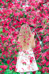 Adorable little girl in blooming apple tree garden on spring day