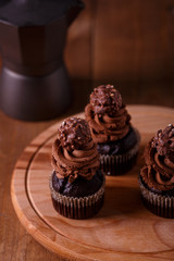 Tasty chocolate cupcakes on wooden board. Dark background