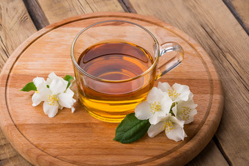Obraz na płótnie Canvas green tea and jasmine flowers, tea with jasmine, tea mug on a wooden board