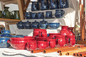 Ceramic mugs and pots, wooden whistles, wooden musical instruments, street market, goods displayed on the table.