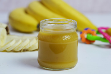 Baby food, banana mashed potatoes and bananas on a white background it is isolated.