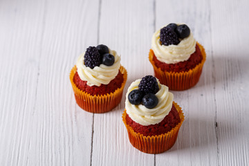 Tasty red velvet cupcakes on wooden table.