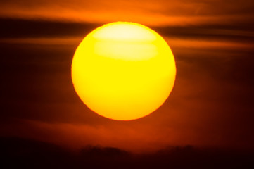 夕空の雲の間をゆく太陽