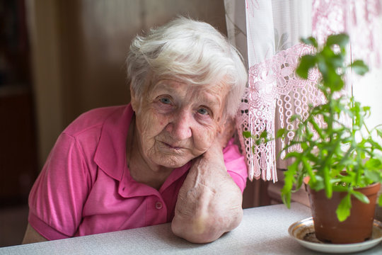 Portrait of elderly woman sitting at the table in the house.
