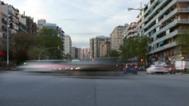 Blurred traffic in Barcelona at dusk.Time Lapse.Trail effect.Long exposure.Scene of unfocused traffic at evening in a main street and vehicles that cross the avenue,with point of view from the asphalt