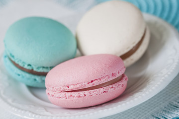 Three macaroons of different colors and different tastes in a white plate, top view. Romantic morning, gift for beloved. Breakfast on Valentin's, Mothers, Women's day. Tender background