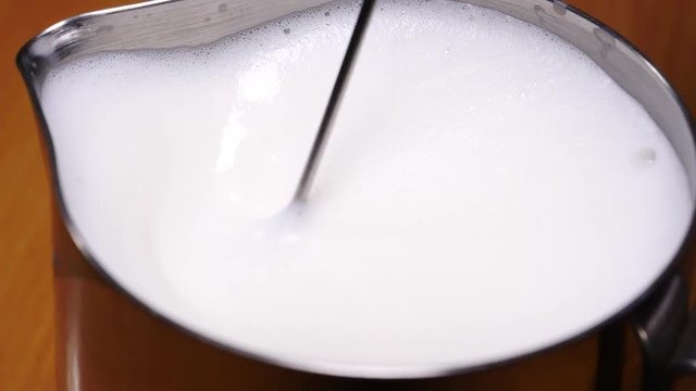 Slow motion shot of frother milk preparing drink for barista purposes, close up.