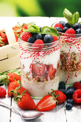 Glass jar of homemade granola with yogurt and fresh berries