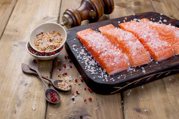 Salmon is sliced  and sprinkled with salt and spices, on a wooden table. Free space for text. Seafood. Healthy food