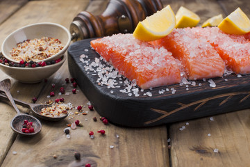 Salmon is sliced  and sprinkled with salt and spices, on a wooden board. Free space for text. Seafood